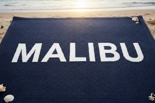 a navy blue blanket that has the word "MALIBU" in bold, block letters printed on it